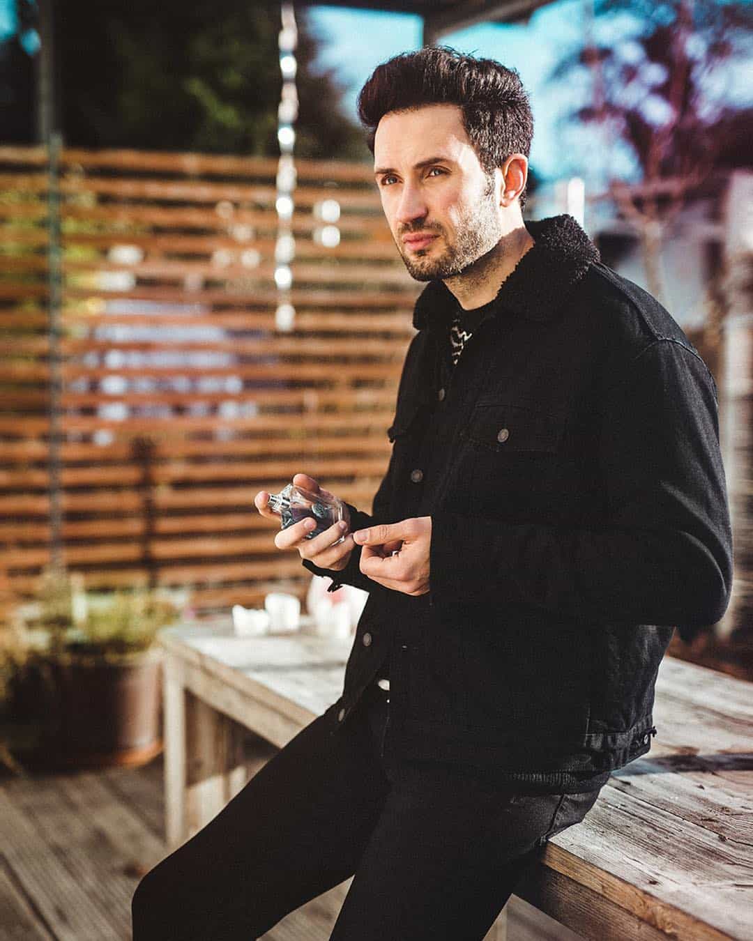 man holding a bottle of pour homme cologne by versace