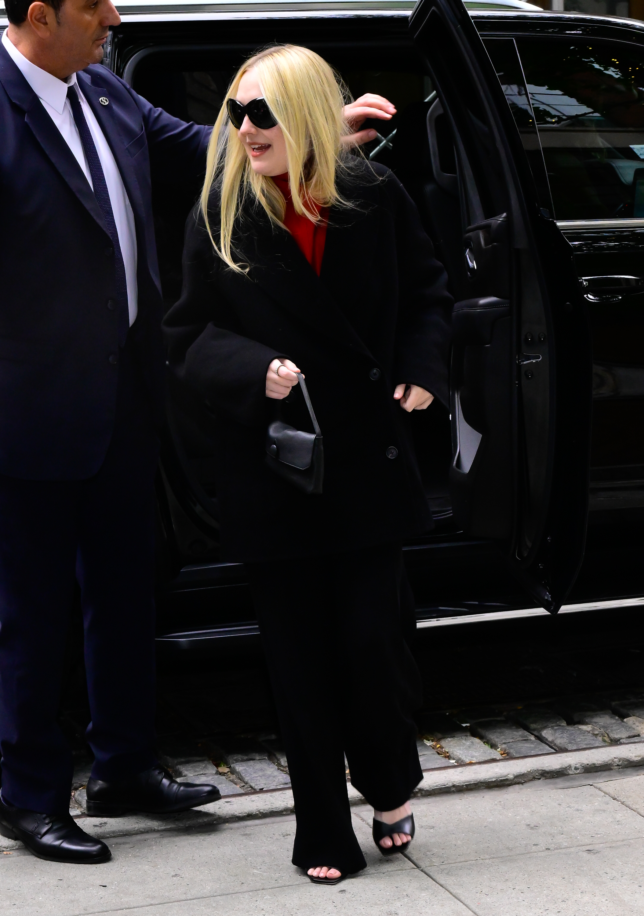 Dakota wears a black jacket, black pants, and the row sally bag.
