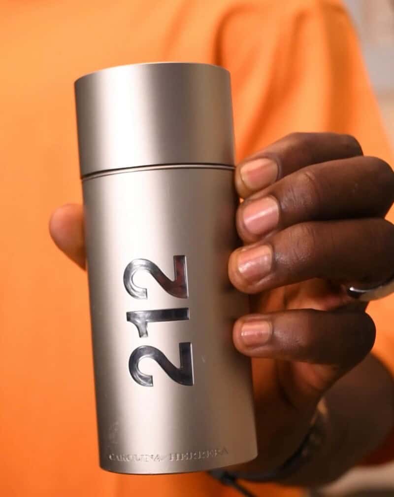 A man holding a bottle of 212 cologne by Carolina Herrera