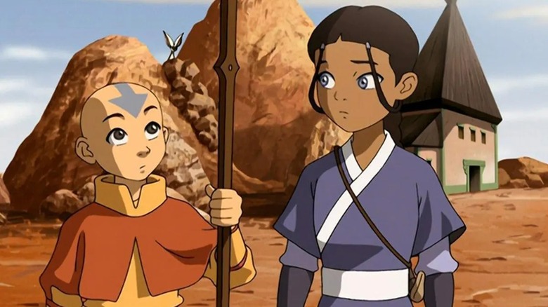 Aang holding a wooden staff next to Katara in 