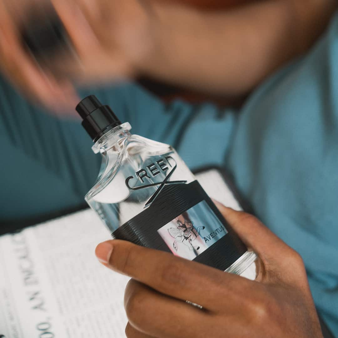 removing the cap of a bottle of cologne 